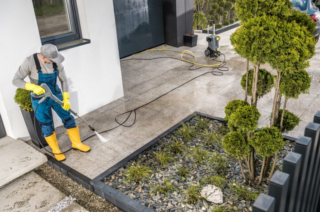 Men Pressure Washing House Surrounding Concrete Elements